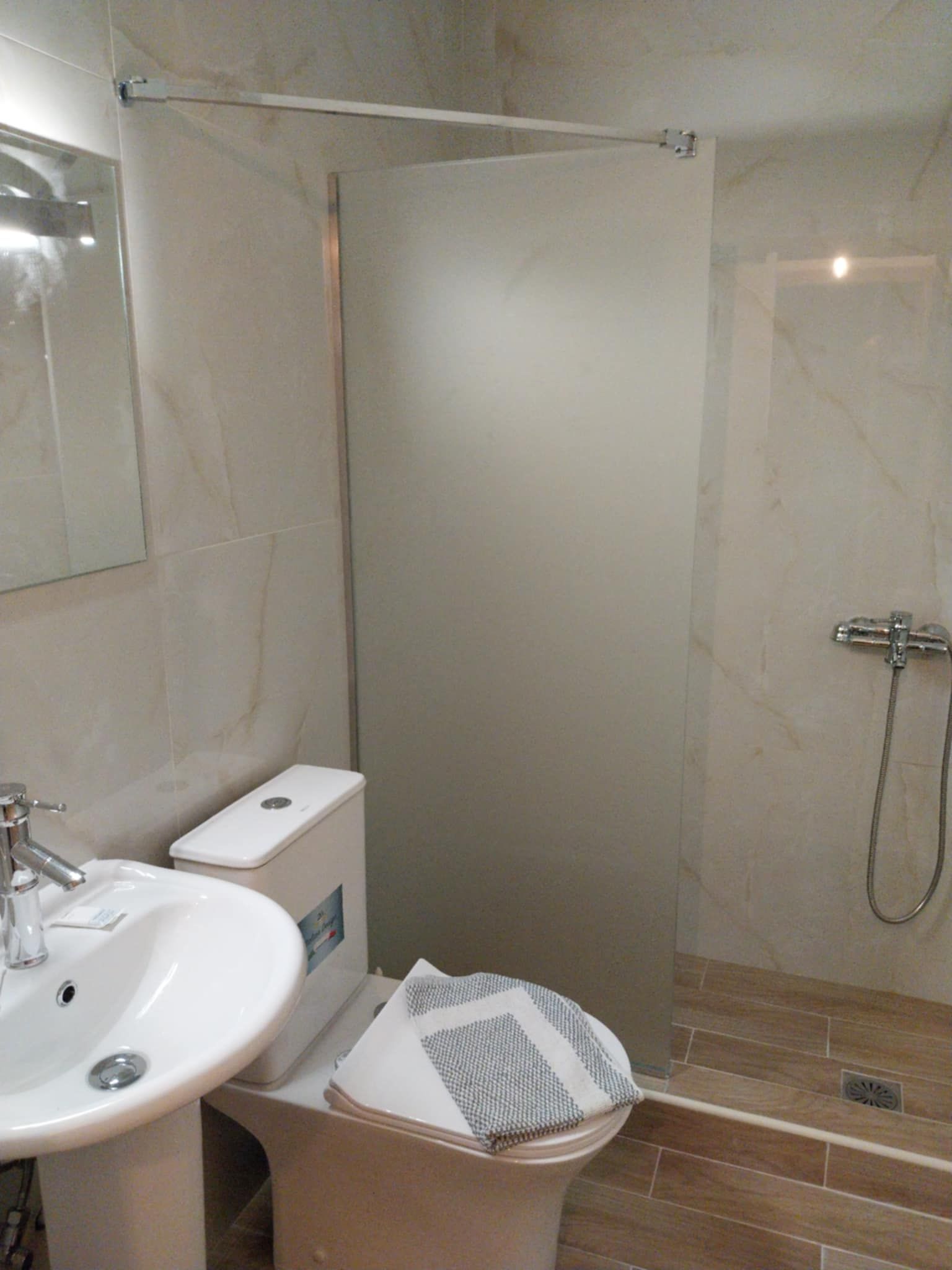 A bathroom with a white sink, toilet, and shower.