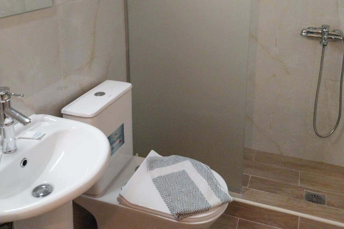 A bathroom with a white sink, toilet, and shower.