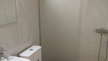 A bathroom with a white sink, toilet, and shower.
