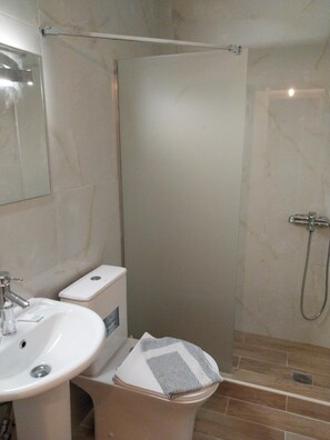 A bathroom with a white sink, toilet, and shower.