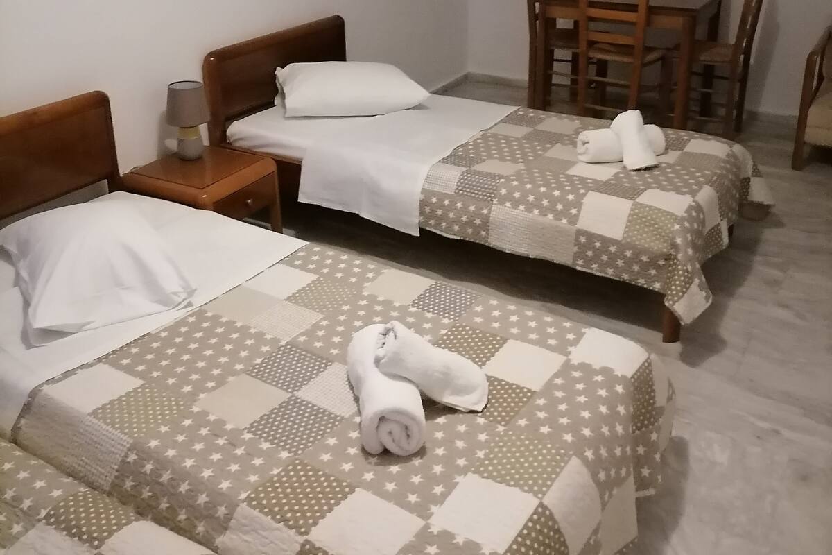 Ein Hotelzimmer mit zwei Betten, einem kleinen Tisch und einem Sessel.