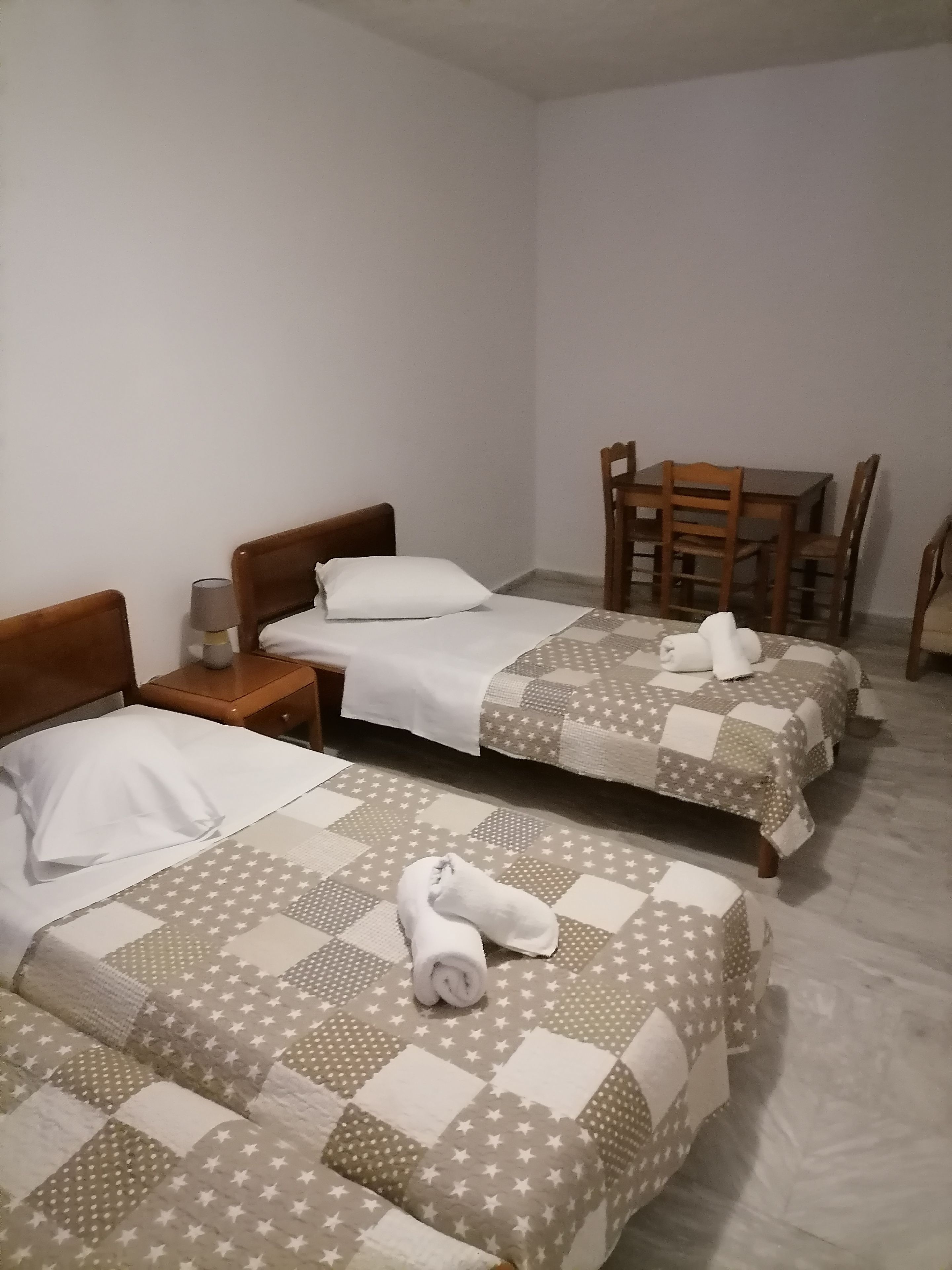 A hotel room with two beds, a small table, and a chair.