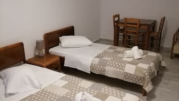 A hotel room with two beds, a small table, and a chair.