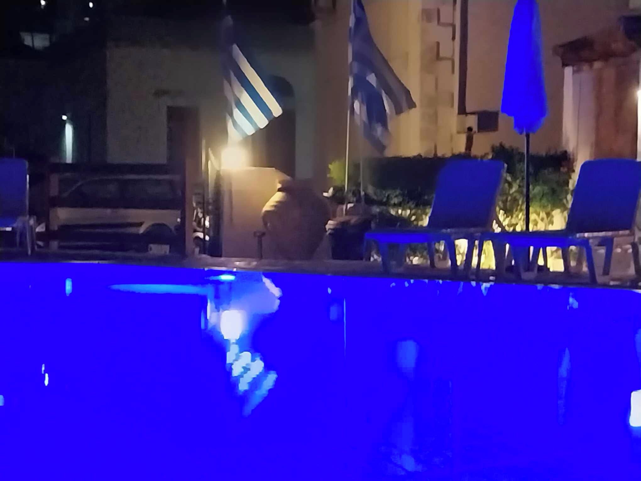 Zona de piscina con sillas de descanso y banderas.