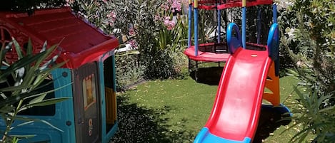 Un parque infantil con un tobogán y una casita de juegos.