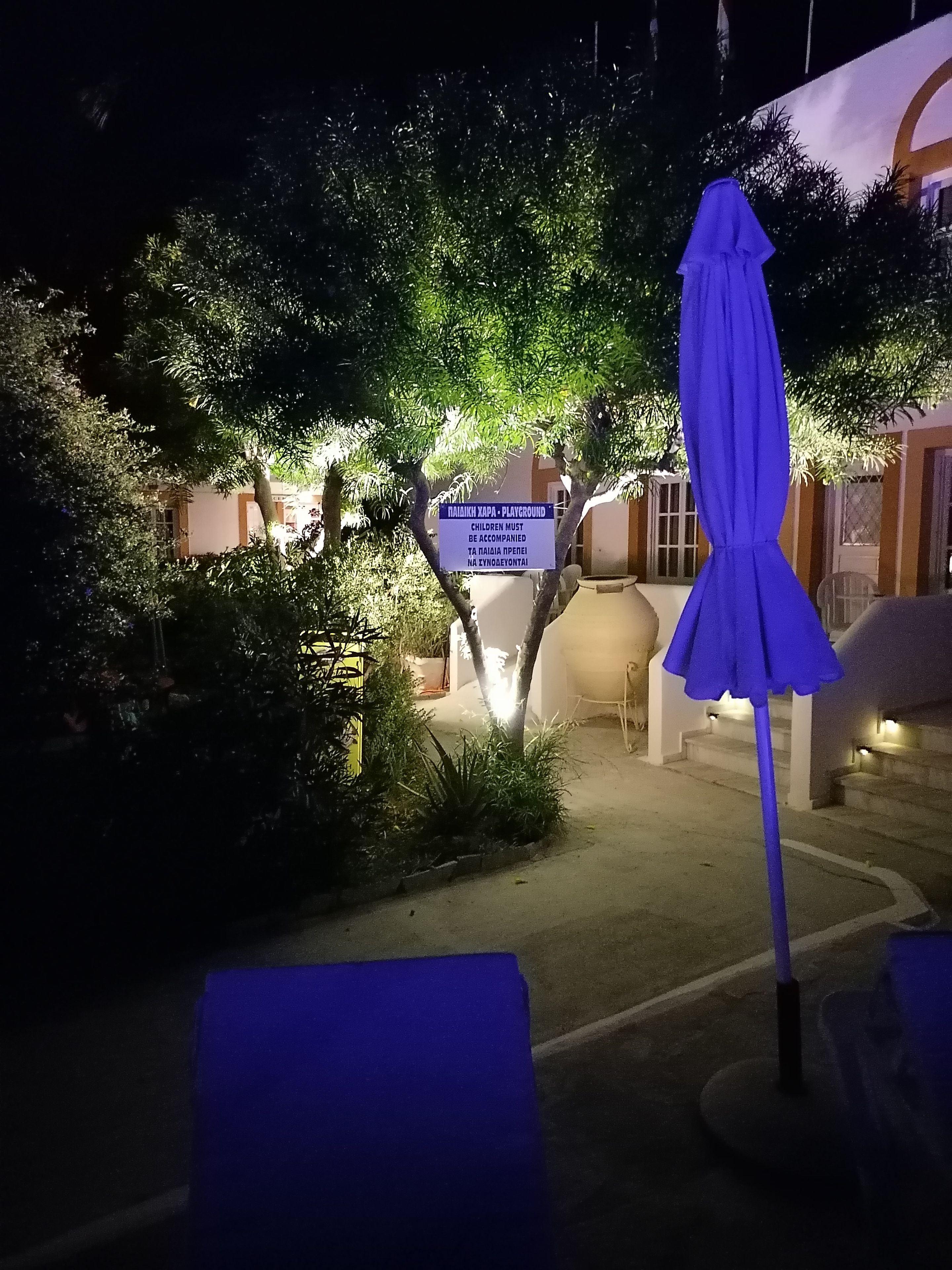 Vista nocturna de un patio de hotel con un letrero que indica una zona de juegos.