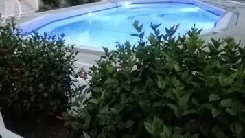 Una piscina circondata dal verde e un edificio bianco con balconi.