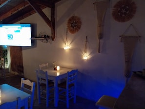 Un comedor con una mesa y sillas blancas, una vela y luces fijadas a la pared.