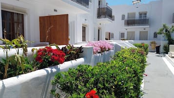 Un edificio blanco con balcones y un jardín con diversas plantas y flores.