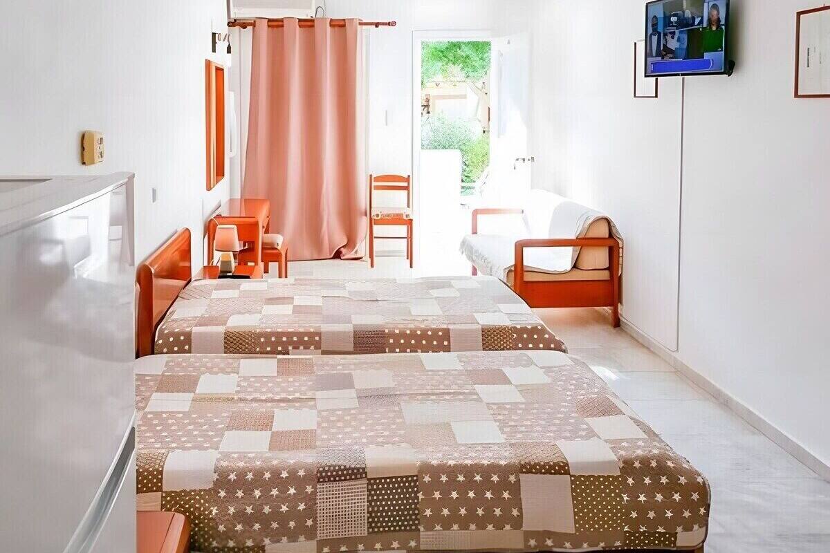 Ein Hotelzimmer mit Bett, zwei Stühlen, einem Schreibtisch und einem Fernseher.