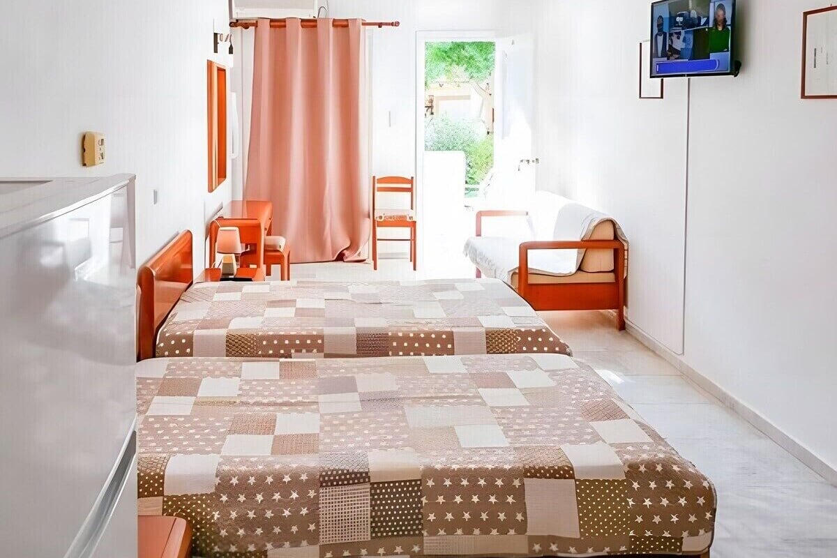 Una camera d'albergo con un letto, due poltrone, una scrivania e una televisione.