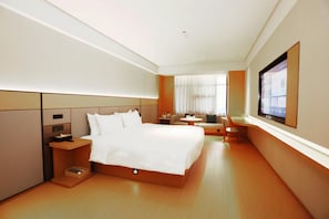 Relax in a spacious room with a large bed, flat-screen TV, and comfortable seating area with a view of the outdoors.