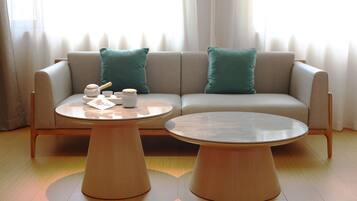 A modern living room with a sofa, two round wooden tables, and a set of tea utensils.