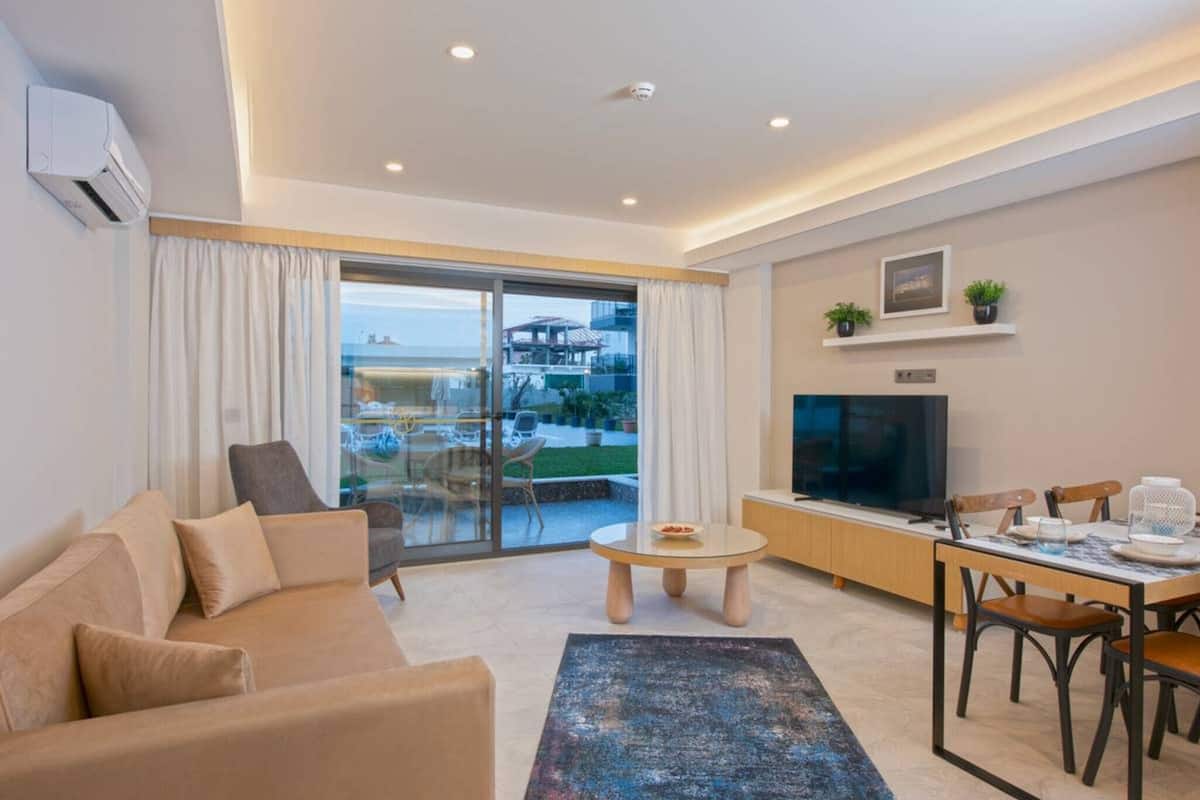 A modern living room with a sofa, a coffee table, a TV, and a dining area.