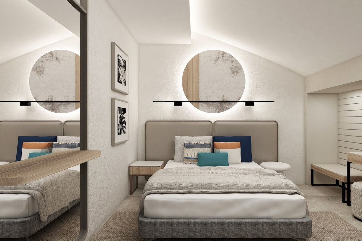 A modern bedroom with a large bed, bedside tables, a mirror, and wall-mounted artwork.