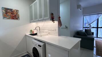 Ett kompakt kök med en inbyggd tvättmaskin, ett handfat och en liten arbetsbänk.