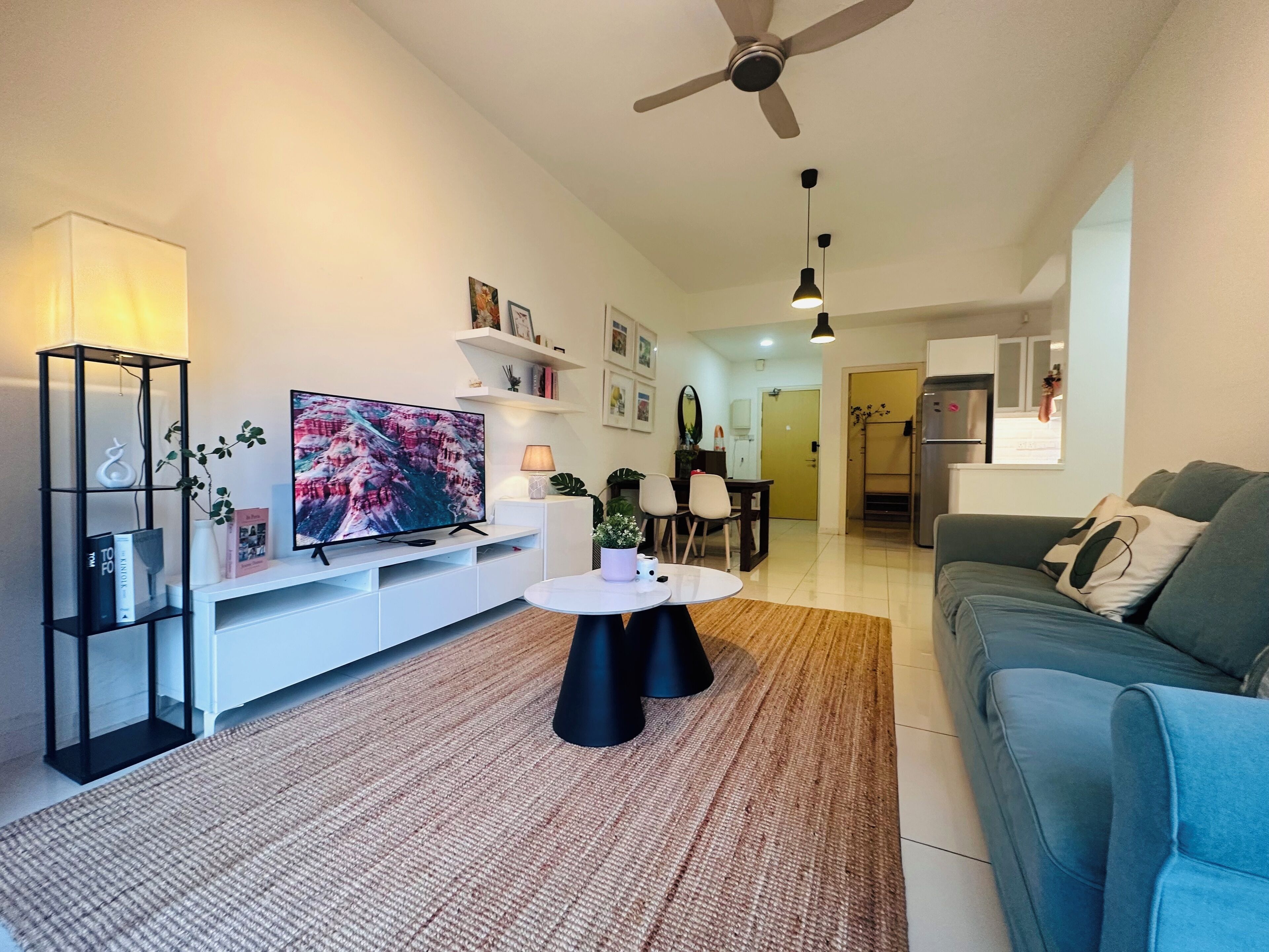 A modern living room with a flat-screen TV, a coffee table, a sofa, and a ceiling fan.