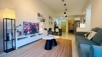 A modern living room with a flat-screen TV, a coffee table, a sofa, and a ceiling fan.