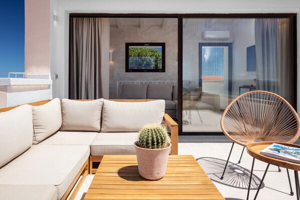 A modern living room with a sofa, a wooden table, a cactus, and a chair.