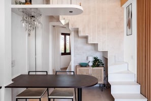 Ein moderner Essbereich mit einem dunklen Holztisch, weißen Wänden und einer Treppe, die zu einer oberen Ebene führt.