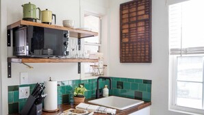 A kitchen with a wooden countertop, a microwave, a coffee maker, and a window with blinds.