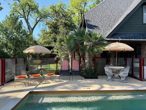 A backyard with a swimming pool, outdoor furniture, and umbrellas.