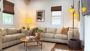 A cozy living room with a wooden ceiling, two sofas, a coffee table, a lamp, and a framed picture on the wall.