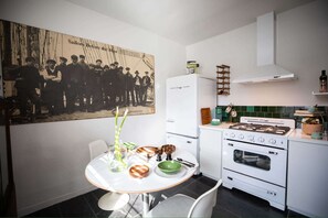 A kitchen with a vintage stove, a refrigerator, and a dining table with chairs.