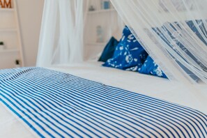 A bed with striped bedding and a canopy.