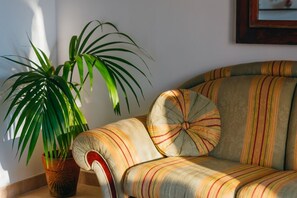 Ein Sofa mit gestreifter Polsterung und einer gepolsterten Rückenlehne, neben einem Blumentopf mit langen, grünen Blättern.