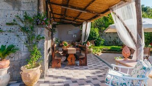 An outdoor patio with a checkered floor, wooden furniture, and potted plants.