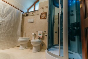A bathroom with two toilets, a shower, and a glass-enclosed shower area.