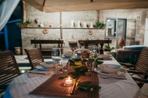 Taula de dinar preparada per a quatre amb una espelma, plats, gots i un suport de fusta.