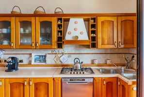 A kitchen with wooden cabinets, a gas stove, a dishwasher, and a kettle.