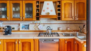 Une cuisine avec des meubles en bois, une cuisinière à gaz, un lave-vaisselle et une bouilloire.