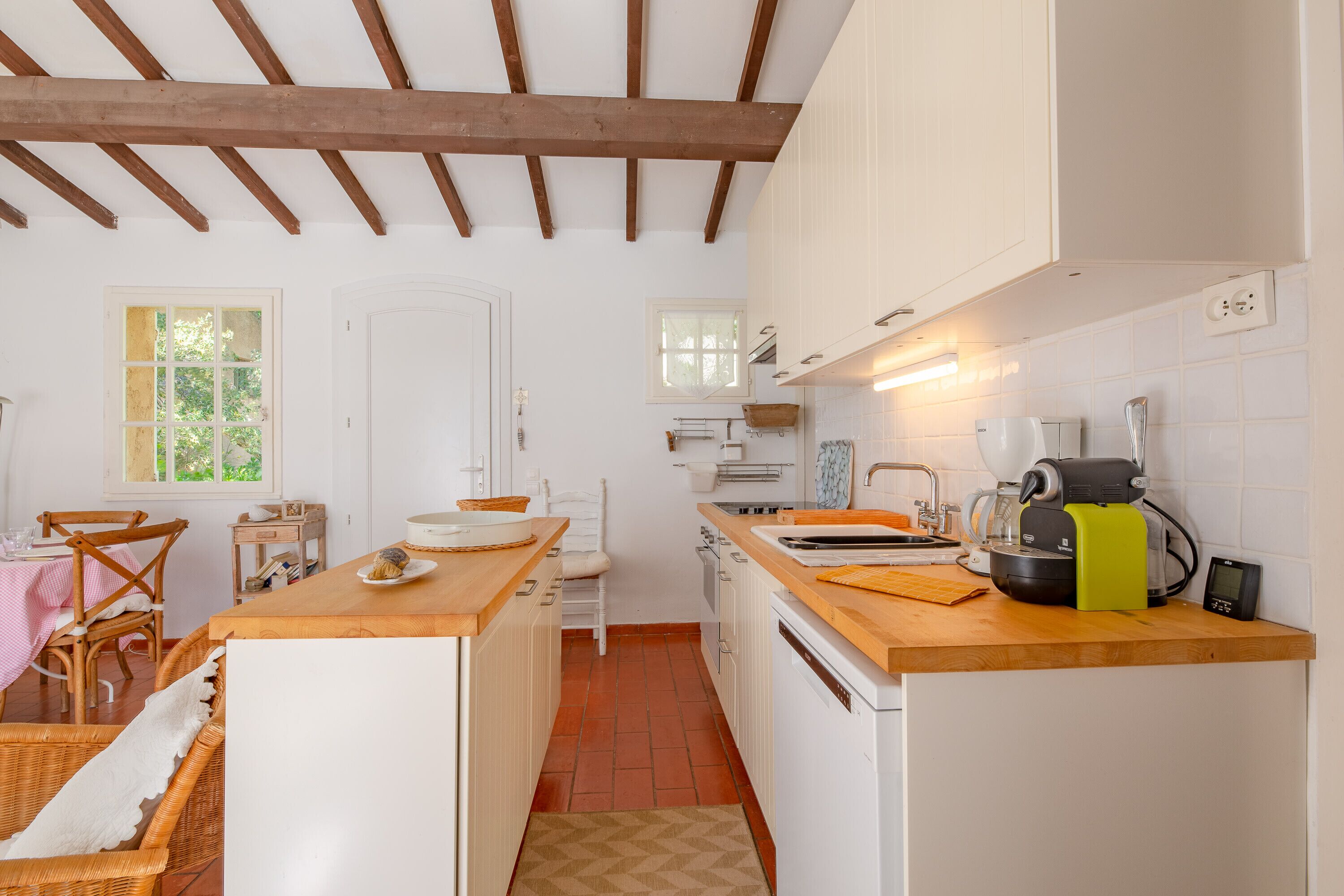 A compact kitchen with white cabinetry, a wooden countertop, and a coffee machine.