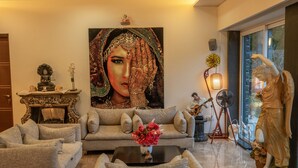 A living room with a sofa, a coffee table with flowers, a statue, and a painting on the wall. - Amã Stays & Trails Butterfly Villa, Deolali, Nashik (Nashik)