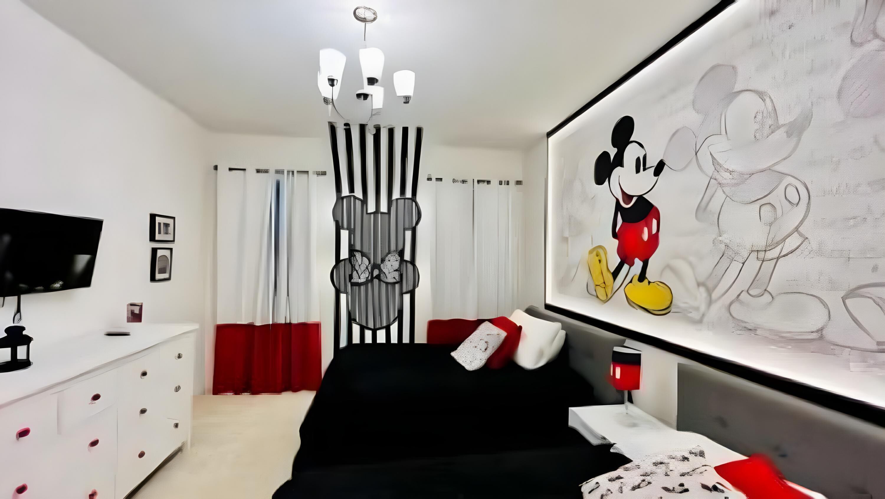 A modern bedroom with a large bed, a flat-screen TV, a desk, and a Mickey Mouse painting.