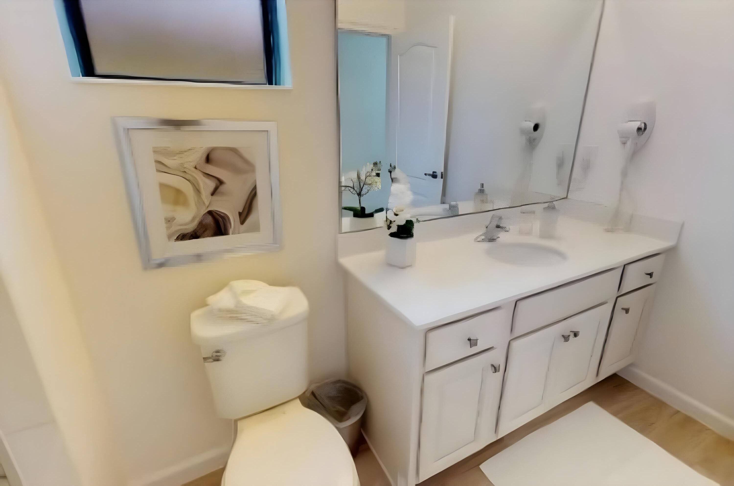 Et moderne badeværelse med en hvid vask, spejl og toilet.