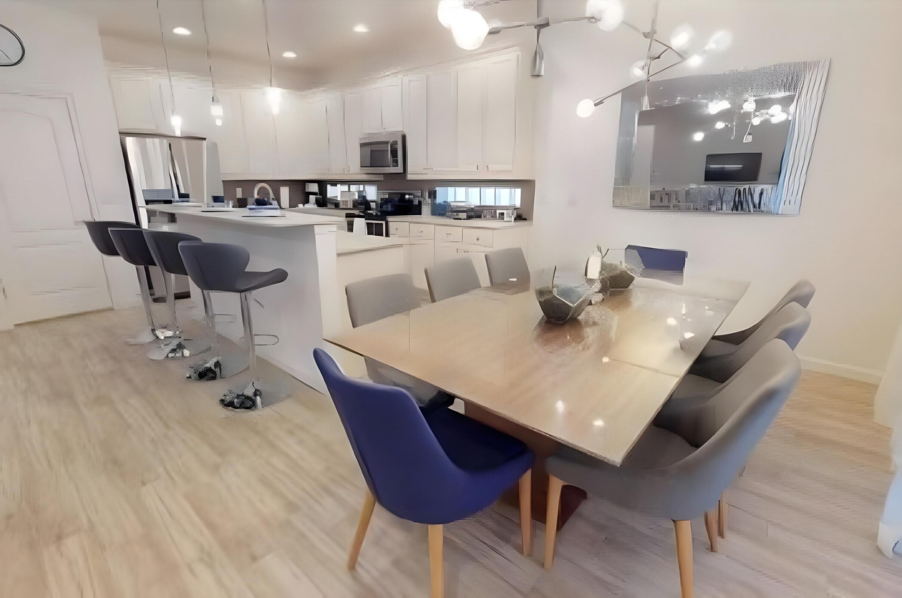 Een moderne keuken met witte kasten, een centraal eiland en een eethoek met een grote tafel en stoelen.