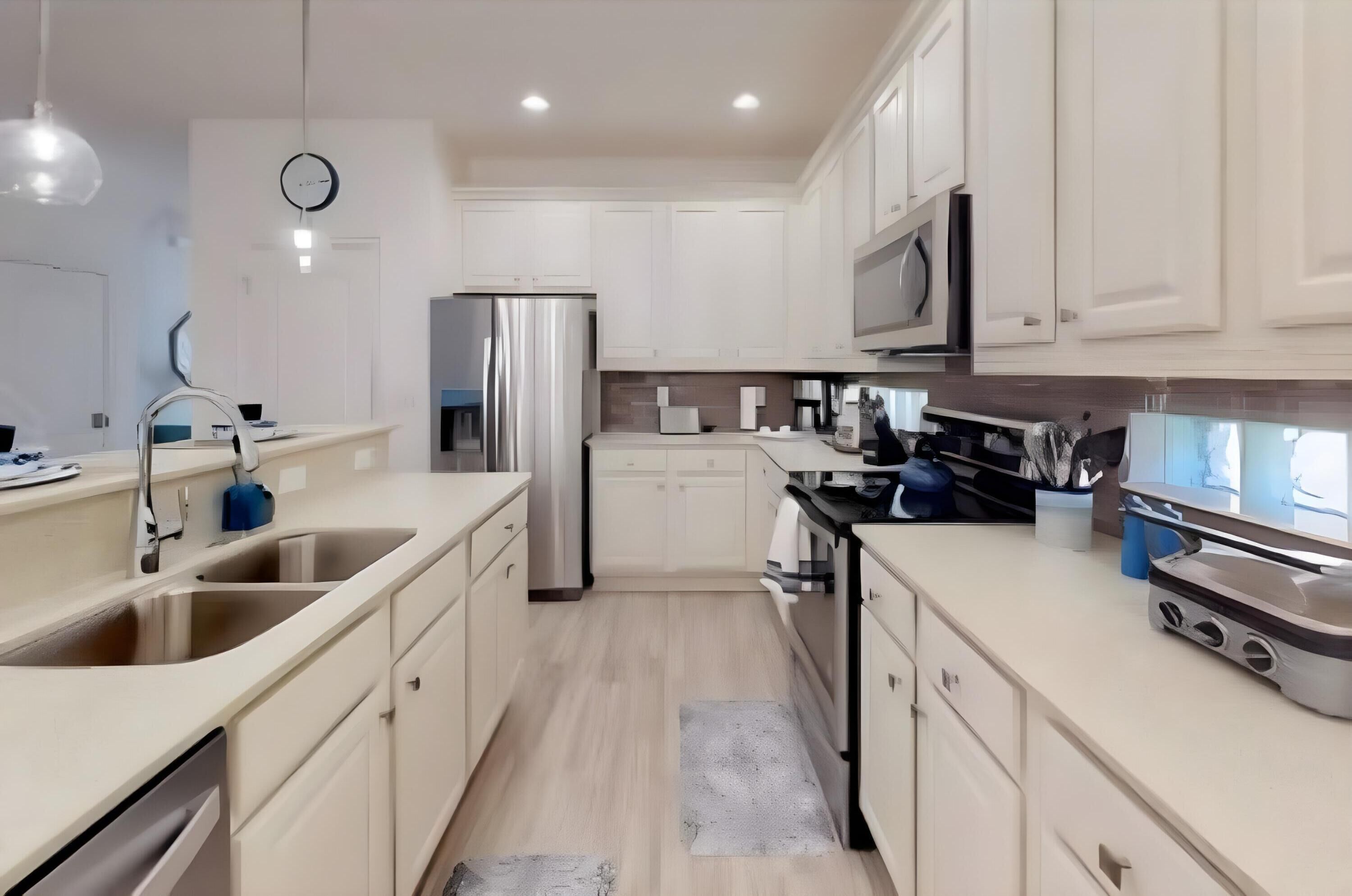 Una cucina moderna con mobili bianchi, elettrodomestici in acciaio inossidabile e un forno a microonde.
