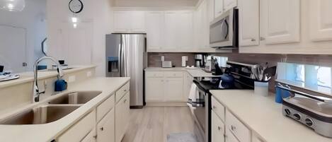 Una cucina moderna con mobili bianchi, elettrodomestici in acciaio inossidabile e un forno a microonde.