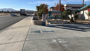 Placa de motel com vista clara dos arredores, incluindo uma estrada com veículos, um passeio e uma montanha ao fundo.