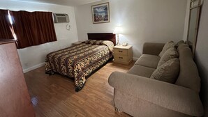 Um quarto com cama, mesa de cabeceira, luminária, sofá e um quadro na parede.