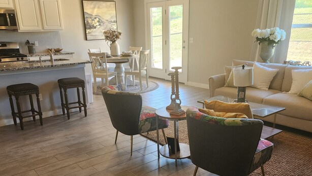 A modern kitchen with white cabinets, a dining area with a round table and chairs, and a living room with a sofa and coffee table. - Entire New home in Edmond, Oklahoma (Edmond)