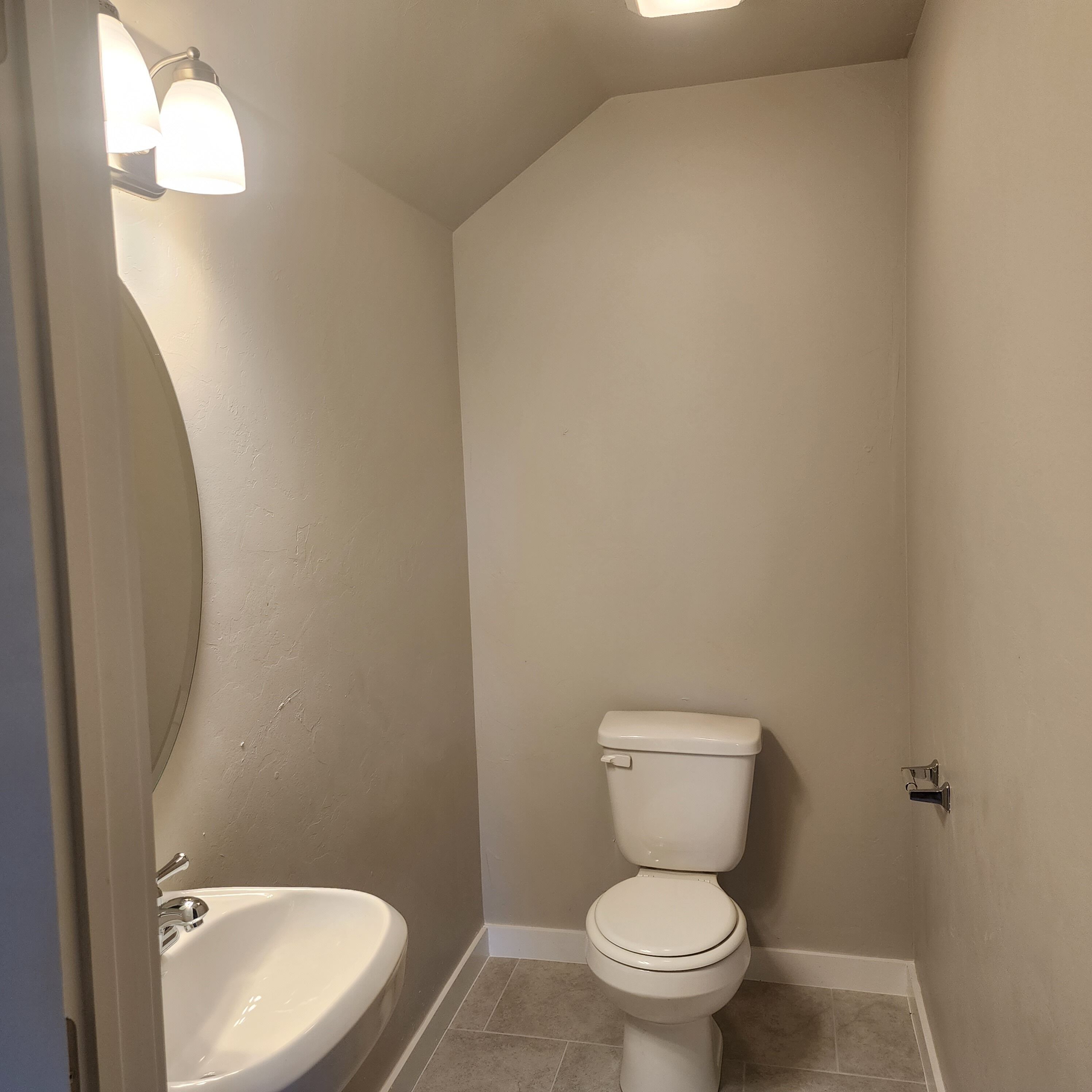 Een badkamer met toilet, wastafel en een wandlamp.