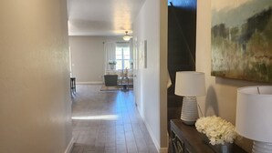 A hallway with wooden flooring, a dark wooden console table with lamps, and a painting on the wall. - Entire New home in Edmond, Oklahoma (Edmond)
