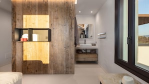 Ein modernes Badezimmer mit einer Wandpaneele aus Holz, einer eingebauten Ablage, einem großen Fenster und Blick ins Freie.