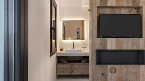 Une salle de bain moderne avec un grand miroir, un lavabo blanc et un meuble-lavabo en bois.