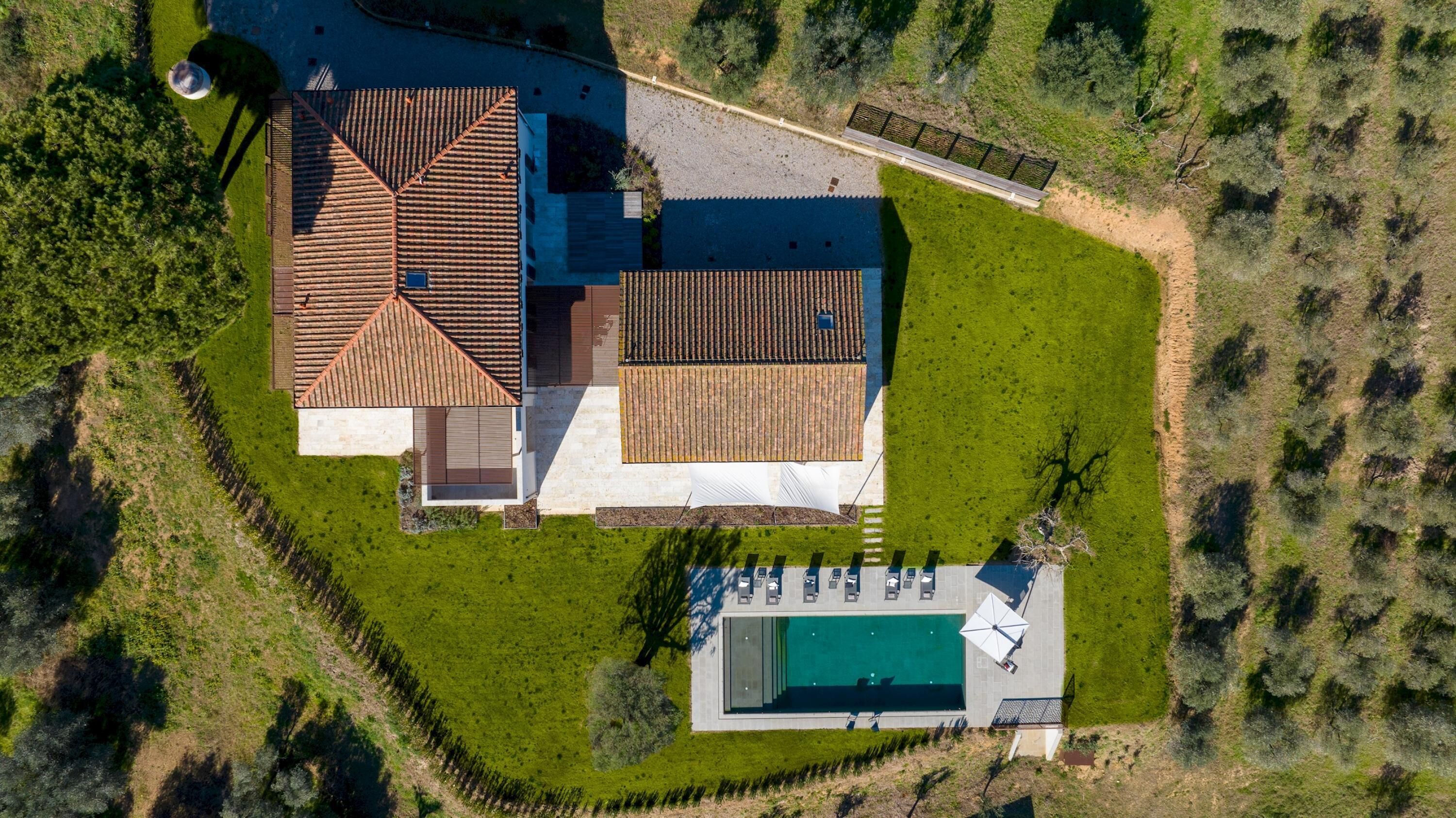 A large house with a swimming pool, surrounded by a well-maintained lawn and a fence.